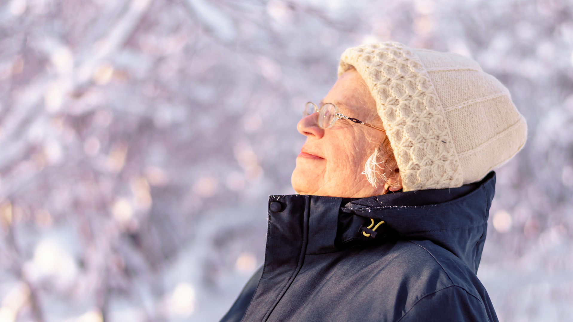 Kvinne i hvit lue myser mot solen