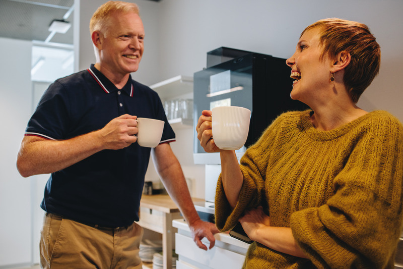 Par med kaffekopper ved kaffemaskinen på jobb.