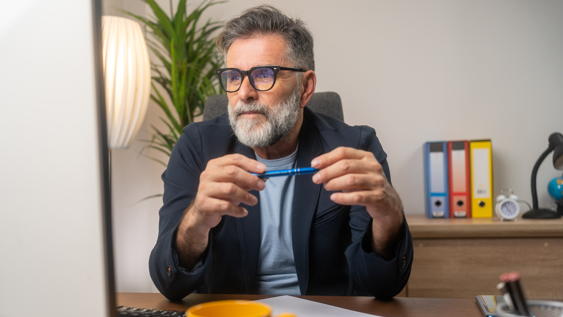 Mann med skjegg og briller ser inn i PCen, antagelig på et hjemmekontor